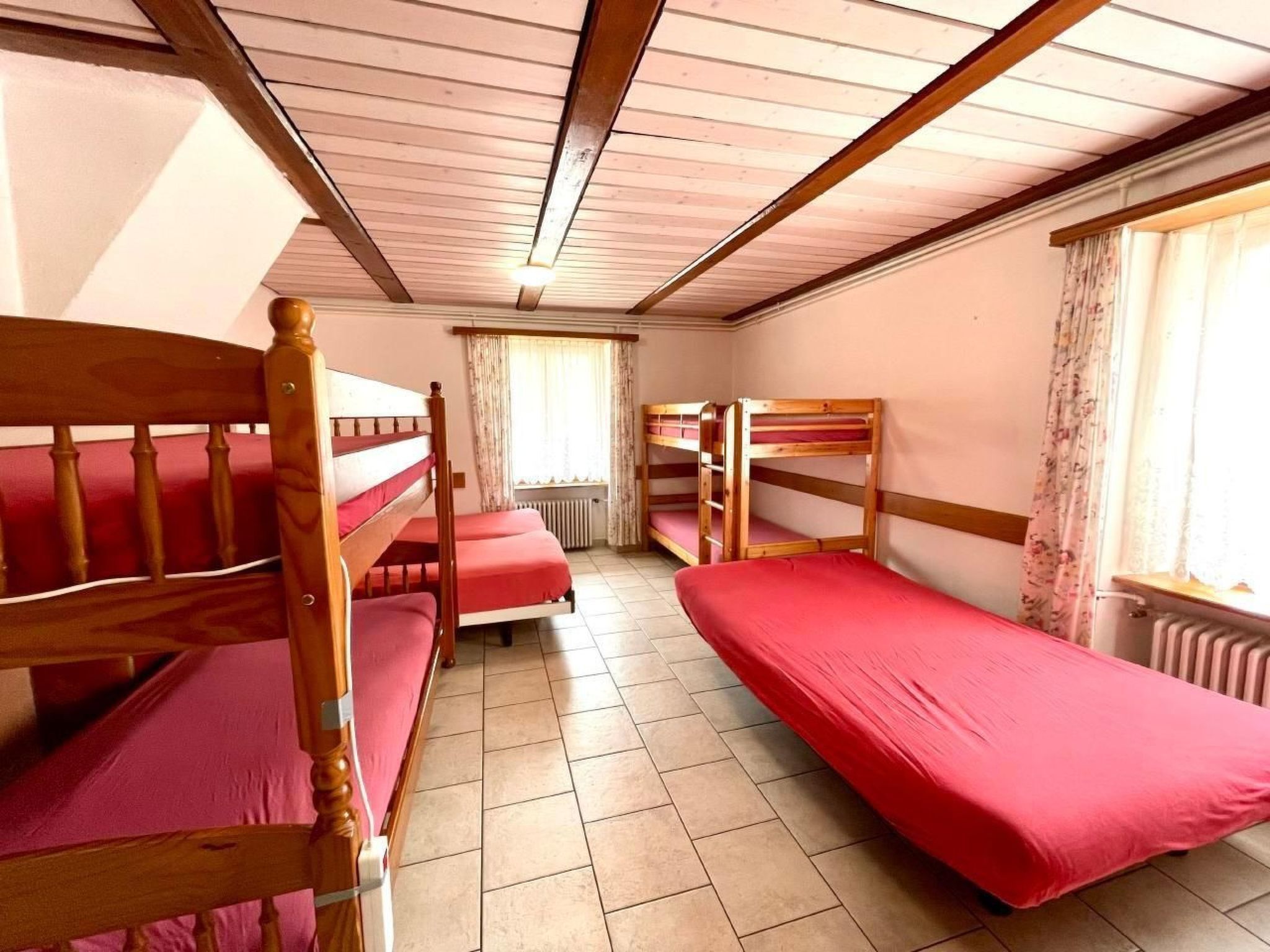 Une chambre de dortoir avec des lits superposés, un radiateur et une fenêtre avec des rideaux.