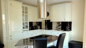 A modern kitchen with white cabinets, a black countertop, and two black chairs. - Fewo Ginkgo II by Interhome (Dresden)