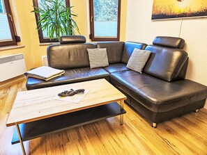 A modern living room with a sectional sofa, a wooden coffee table, and a large window with blinds. - Fewo Ginkgo by Interhome (Dresden)