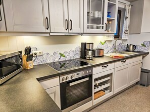 Una cocina moderna con horno empotrado, cafetera y estante para vinos.