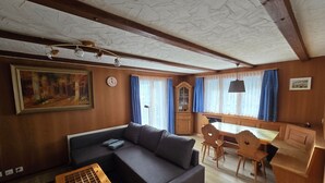 Una sala de estar acogedora con un sofá modular, una mesa de centro de madera y un comedor con una mesa y sillas de madera.