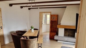 Un vaste espace de vie doté d’un plancher en bois, d’un canapé, d’une table avec des chaises et d’une cheminée.