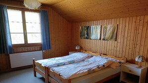 Een slaapkamer met houten lambrisering, een bed, nachtkastjes en een radiator.