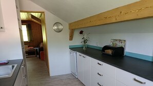 Een moderne keuken met witte kasten, een zwart aanrecht en een houten balk in het plafond.