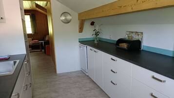 Een koelkast, een oven, een vaatwasser, kookgerei, borden en bestek