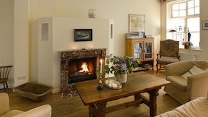 Ein gemütliches Wohnzimmer mit Kamin, einem Holztisch und bequemen Sitzgelegenheiten.