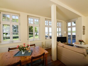 A dining area with a wooden table and chairs, a sofa, and a television. - Wohnung im ersten Obergeschoss des Gutshauses by Interhome (Gingst)