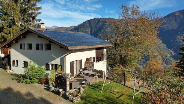 Ein Haus mit geneigtem Dach, Solaranlagen und einem Steinfundament.