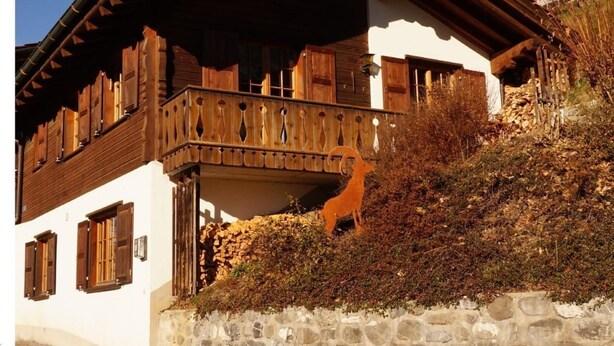 En traditionell chalet med en grund av sten, en träbalkong och träpersienner.