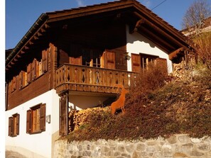 A traditional chalet with a stone foundation, wooden balcony, and wooden shutters. - Ferienhaus Stutz Hausteil rechts by Interhome (Küblis)
