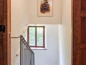 A staircase with a metal railing leading to a window with a view of greenery outside. - Waterfall House by Interhome (Mesocco)