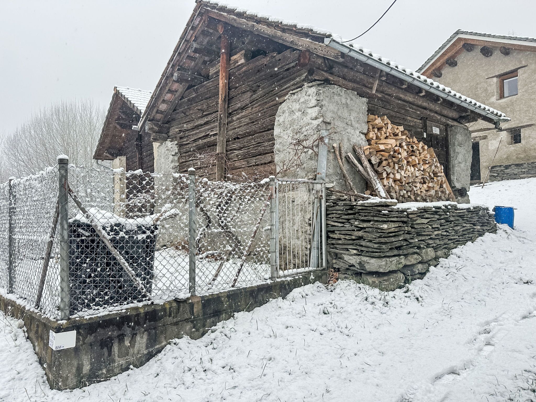 Una rustica baita di legno con fondamenta in pietra, immersa in un paesaggio innevato.