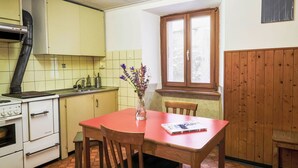 A compact kitchen with a stove, sink, and cabinets. There is a dining table with chairs and a window with a view. - Waterfall House by Interhome (Mesocco)
