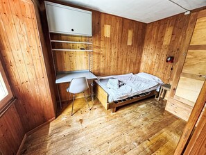A compact room with a bed, a desk, and a chair. - Waterfall House by Interhome (Mesocco)