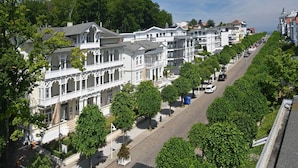 Eine Reihe weißer Gebäude im viktorianischen Stil mit einer Straße dazwischen, gesäumt von Bäumen.