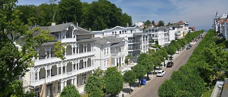 Eine Reihe weißer Gebäude im viktorianischen Stil mit einer Straße dazwischen, gesäumt von Bäumen.
