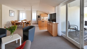 Eine moderne Wohnung mit Essbereich, Küche und einem Balkon mit Sitzgelegenheit.