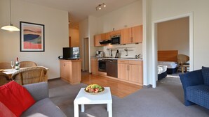 A modern living room with a sofa, a dining table, and a kitchen area with wooden cabinets and appliances. - Villa Celia Sellin by Interhome (Ostseebad Sellin)