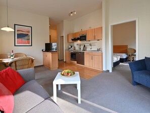 A modern living room with a sofa, a dining table, and a kitchen area with wooden cabinets and appliances. - Villa Celia Sellin by Interhome (Ostseebad Sellin)