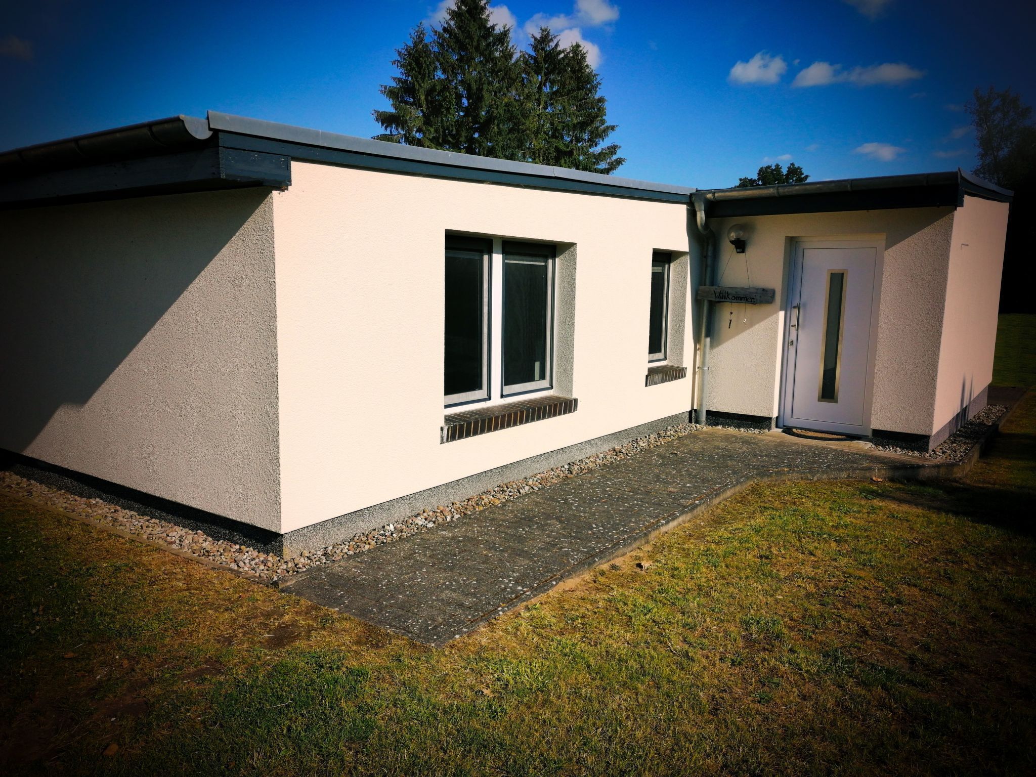 Ein modernes Gebäude mit flachem Dach, einer kleinen Veranda und einer Tür.