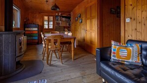 Ein gemütliches Blockhaus-Interieur mit einem Holzespeisetisch, Stühlen, einem Kamin, einer Ledersofa und einem Bücherregal.