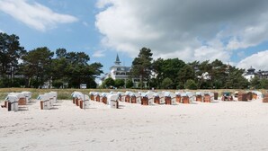 A beach with rows of beach huts and a large building with a spire in the background. - Villa Seeblick Binz by Interhome (Binz)