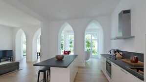 A modern kitchen with an island, white cabinetry, and a large window. - Villa Seeblick Binz by Interhome (Binz)