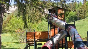 A playground with multiple slides and a wooden bench. - Ski-in Wohnung in Anzere mit Parkplatz by Interhome (Anzère)