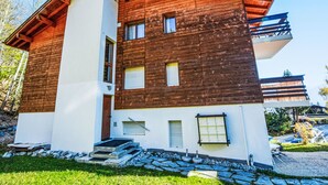 A modern two-story building with a wooden facade and a white lower section. - Ski-in Wohnung in Anzere mit Parkplatz by Interhome (Anzère)