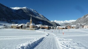 A snow-covered village with a church, buildings, and mountains in the background. - Bijou - BioBergün by Interhome (Bergün)