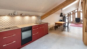A kitchen with a skylight, red cabinets, and a wooden dining table. - Bijou - BioBergün by Interhome (Bergün)