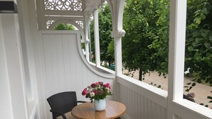 Eine überdachte Veranda mit einem runden Holztisch und zwei Korbstühlen.