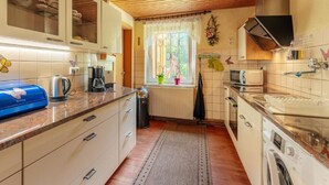 A compact kitchen with wooden ceiling, white cabinets, a built-in oven, and a washing machine. - Vacation home Zita by Interhome (Thale)