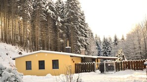 A yellow building with a fenced yard, surrounded by snow-covered trees. - Vacation home Zita by Interhome (Thale)