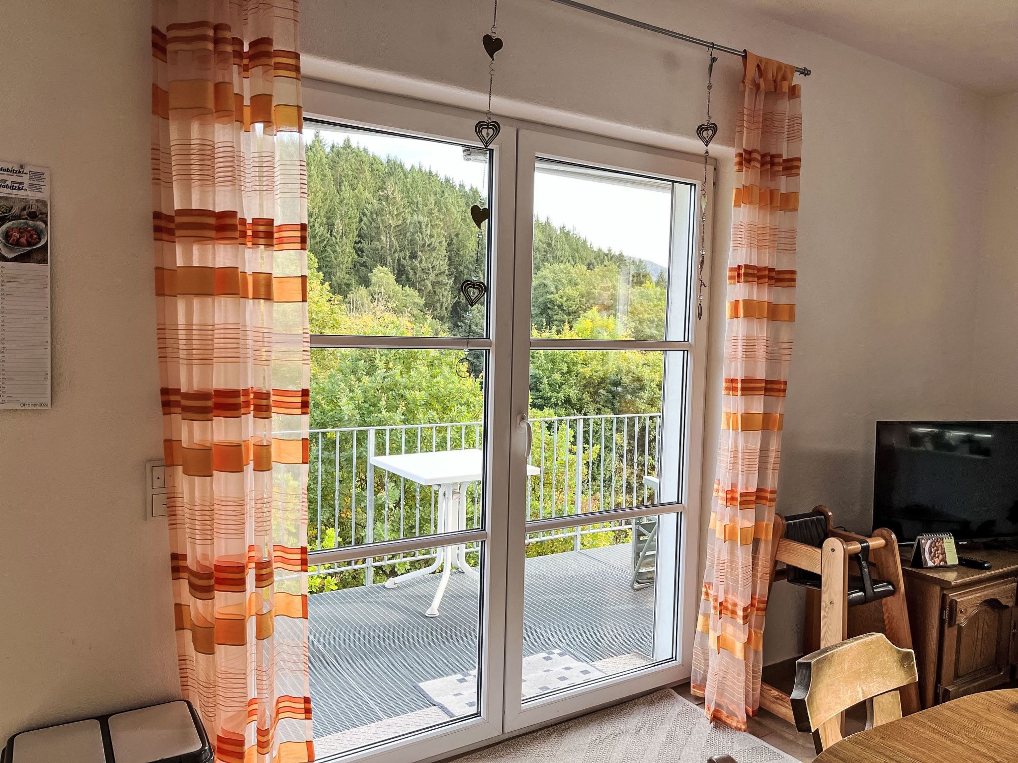 A room with a sliding glass door leading to a balcony with a table and chairs.