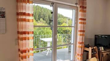 Ein Zimmer mit einer Schiebeglastür, die auf einen Balkon mit Tisch und Stühlen führt.