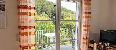 A room with a sliding glass door leading to a balcony with a table and chairs.