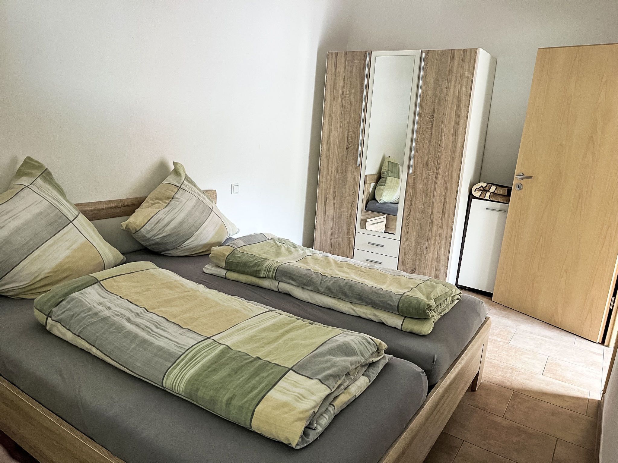 Ein Zimmer mit einem Bett, einem Kleiderschrank und einem Spiegel.