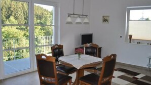 Un comedor con una mesa y sillas, un televisor y una ventana con vistas a árboles.
