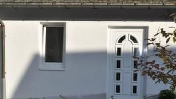 Un edificio con fachada blanca, una ventana y una puerta.