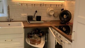 Eine kompakte Küche mit weißen Schränken, einem eingebauten Backofen und einer Arbeitsfläche mit Wasserkocher und Kaffeemaschine.