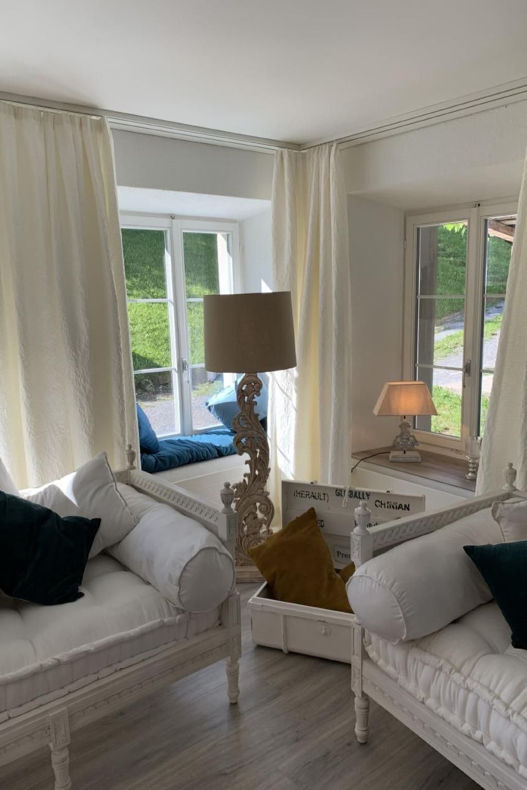 A room with two white sofas, a decorative table, and a view of greenery outside.
