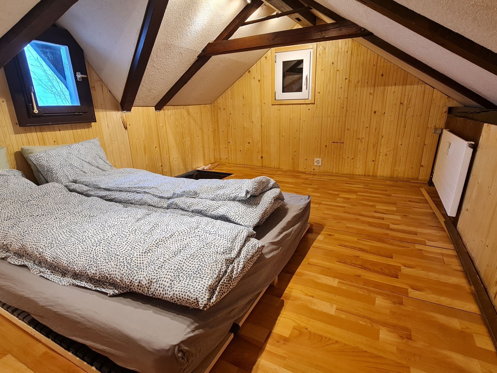 Un dormitorio acogedor en el ático, con paredes de madera y techo inclinado.