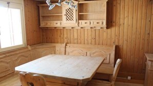 Un comedor de madera con una mesa grande, sillas, estantes empotrados y una ventana.