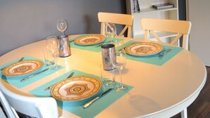 Une table à manger dressée avec des sets de table, des assiettes, des couverts et des verres, et une bibliothèque en arrière-plan.