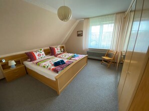 A bedroom with a large bed, a bedside table with a lamp, a chair, and a radiator. - Geräumige Ferienwohnung mit Garten und Grill by Interhome (Hage)