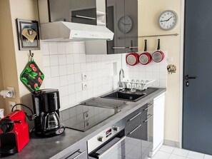 Une cuisine moderne équipée d’une cuisinière en acier inoxydable, d’une machine à café et d’une bouilloire.