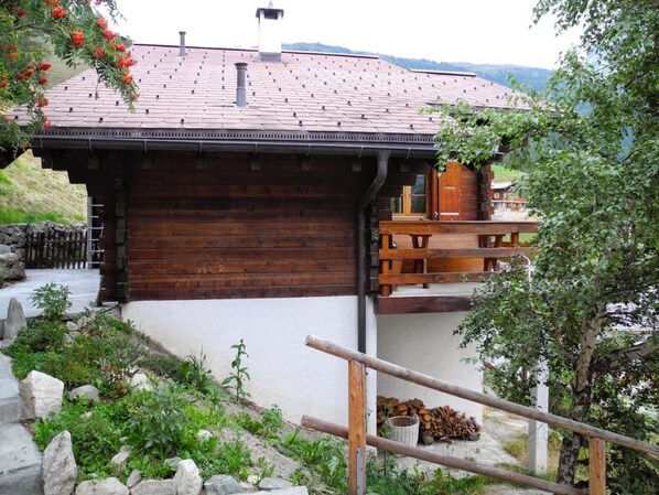 Une cabane rustique avec une façade en bois, des fondations en pierre et un toit recouvert de tuiles rouges.