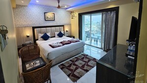 Ein modernes Hotelzimmer mit einem großen Bett, einem Schreibtisch mit Stuhl, einem Balkon mit Blick und einem Deckenventilator.