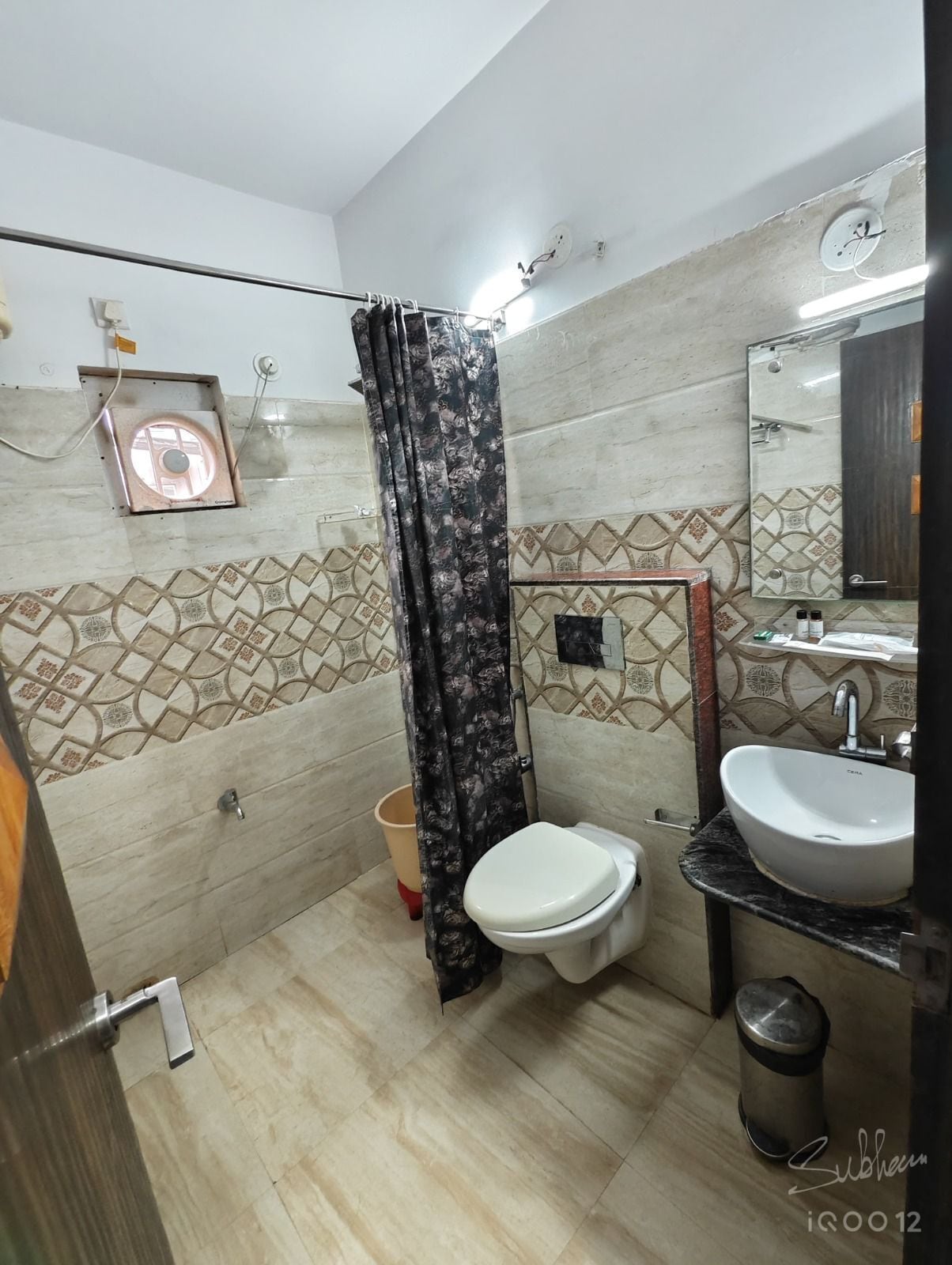 A bathroom with a toilet, sink, and shower curtain.
